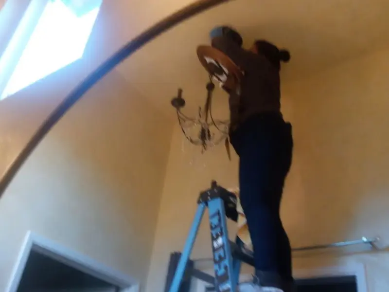 Electrician installing a chandelier in a Ashland residence
